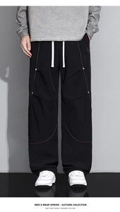 Détail du pantalon cargo noir avec coutures orange contrastées et cordon de serrage blanc