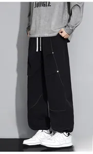 Détail du pantalon cargo noir ample avec coutures orange et ourlets à cordon de serrage