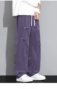 Détail du pantalon parachute cargo violet avec surpiqûres jaunes et ferrures métalliques