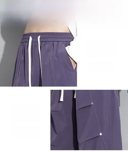 Détail du pantalon parachute violet avec taille élastique, cordon blanc et coutures orange