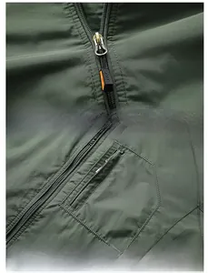 Detail of high-quality smooth zipper and vertical chest pocket on dark green outdoor jacket