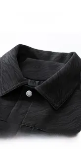 Detailed close-up of a black twill jacket featuring a lapel collar and silver metal button