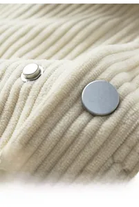 Detailed macro view of silver metal snap buttons on beige corduroy jacket fabric