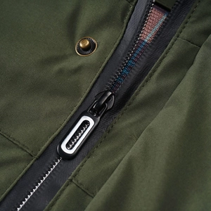 Detailed close-up of military green jacket fabric with matte black zipper and bronze snap