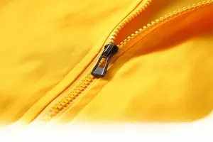 Macro detail of high-quality smooth zipper and fabric texture on yellow casual jacket