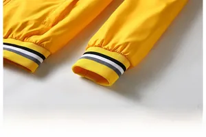 Detail of bright yellow jacket featuring elastic ribbed cuffs with black and white stripes