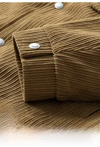 Close-up of brown corduroy sleeve cuff with silver metal button and textured fabric