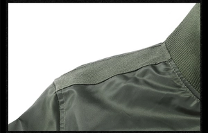 Detailed macro view of military green bomber jacket shoulder seam and nylon fabric texture