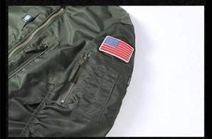 Detail of army green flight jacket sleeve with US flag patch and zipper utility pocket