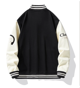 Flat lay of a black and white varsity jacket with letter embroidery and striped ribbing
