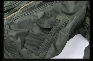 Detail of heavy-duty brass zipper and durable olive green nylon fabric on pilot jacket