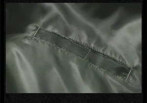 Detailed close-up of dark olive flight jacket fabric texture and reinforced inner pocket seam