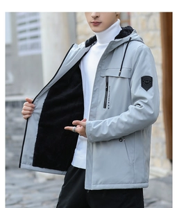 Detail of grey hooded outdoor jacket featuring fleece lining and arm badge embroidery