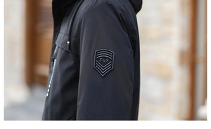 Close-up of black fleece jacket sleeve with F&S shield badge and windproof texture