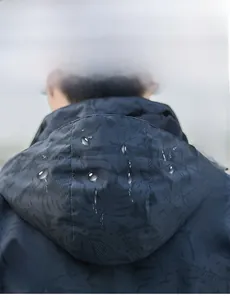 Détail de veste à capuche imperméable avec motif de feuilles camouflage et déperlant durable