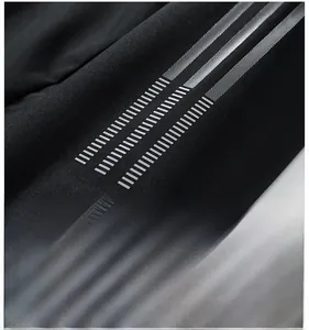 Detail of black outdoor jacket sleeve featuring three silver reflective striped accents