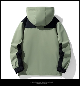 Back view of a sage green and black waterproof outdoor jacket with a hood and embroidery
