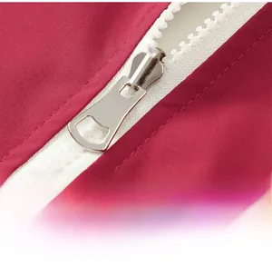 Vue macro détaillée de la fermeture éclair en plastique blanc sur une veste en tissu rouge
