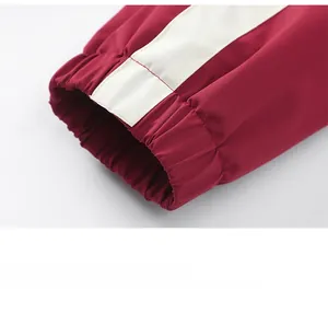 Détail du poignet élastique d'un coupe-vent rouge et blanc avec des coutures précises