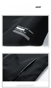 Close-up of black windbreaker featuring white letter print and hidden zipper pocket