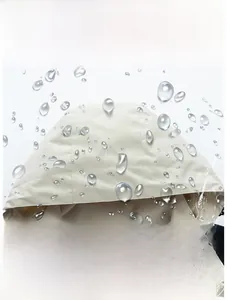 Detail of waterproof breathable fabric with water droplets on a beige outdoor jacket