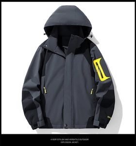 Detail of waterproof outdoor jacket featuring grey color-block and yellow zipper