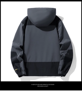 Detail view of hooded outdoor jacket with contrast panels and embroidered sleeve cuff
