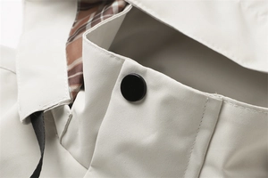 Dettaglio della giacca beige con bottone nero e fodera classica a quadri all'interno