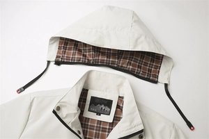 Dettaglio giacca beige con cappuccio, fodera classica a quadri marrone rosso e colletto