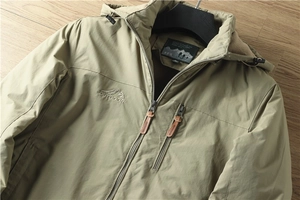 Détail d'une veste d'extérieur kaki avec broderie de montagne et tirettes en cuir