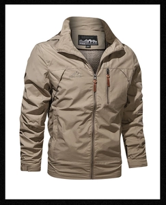 Detail of outdoor windproof jacket showing zippered chest pocket and mountain peak logo