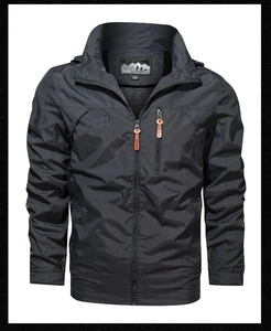 Close-up of dark grey outdoor jacket with orange zipper pulls and mountain embroidery