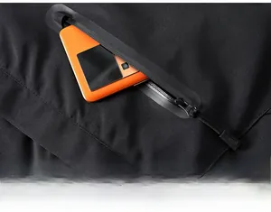 Détail de la poche à fermeture éclair étanche sur veste chauffante avec téléphone orange