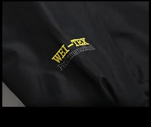 Close-up of WEI-TEX PerformanceShell embroidery on black waterproof outdoor jacket
