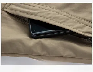 Dettaglio macro della tasca con cerniera della giacca outdoor kaki con spazio per cellulare