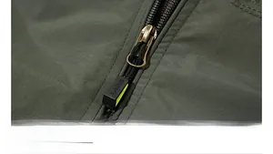Detailed macro view of the durable bronze zipper with SPORTS puller on outdoor jacket