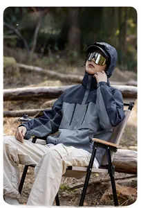 Detail view of a color-block waterproof hiking jacket with multiple functional pockets