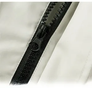 Dettaglio della cerniera nera su una giacca a vento outdoor grigio chiaro