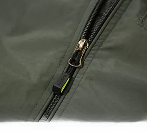 Detail shot of army green jacket zipper with bronze puller and SPORTS embossed cord