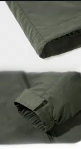 Detail of dark green outdoor jacket showing adjustable velcro cuffs and smooth hemline