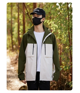 Outdoor male model wearing a color-block olive green and cream windbreaker in a forest