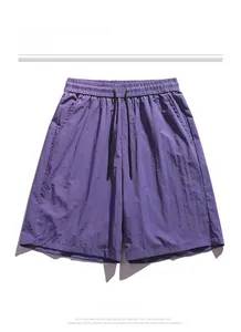 Detail of purple quick-dry shorts featuring elastic drawstring waist and logo print