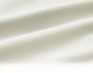 Close-up detail of high-quality cream white textile fabric with fine woven texture