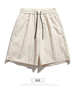 Detail view of beige quick-dry shorts with elastic waistband and mountain embroidery