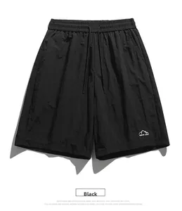 Detail of black quick-dry shorts featuring an elastic drawstring waist and mountain logo print