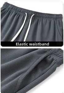 Detail view of elastic drawstring waistband and side pockets on ribbed gray trousers