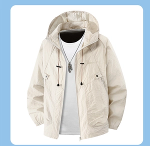 Flat lay of beige sun protection jacket with drawstring hood and layered accessories