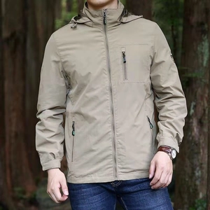 Men's khaki hooded outdoor jacket with multiple zip pockets in a forest setting