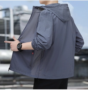 Détail d'une veste de protection solaire grise à capuche avec zips rouges pour homme