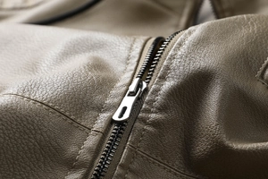 Gros plan sur le zip métallique et la texture grainée du cuir de la veste marron